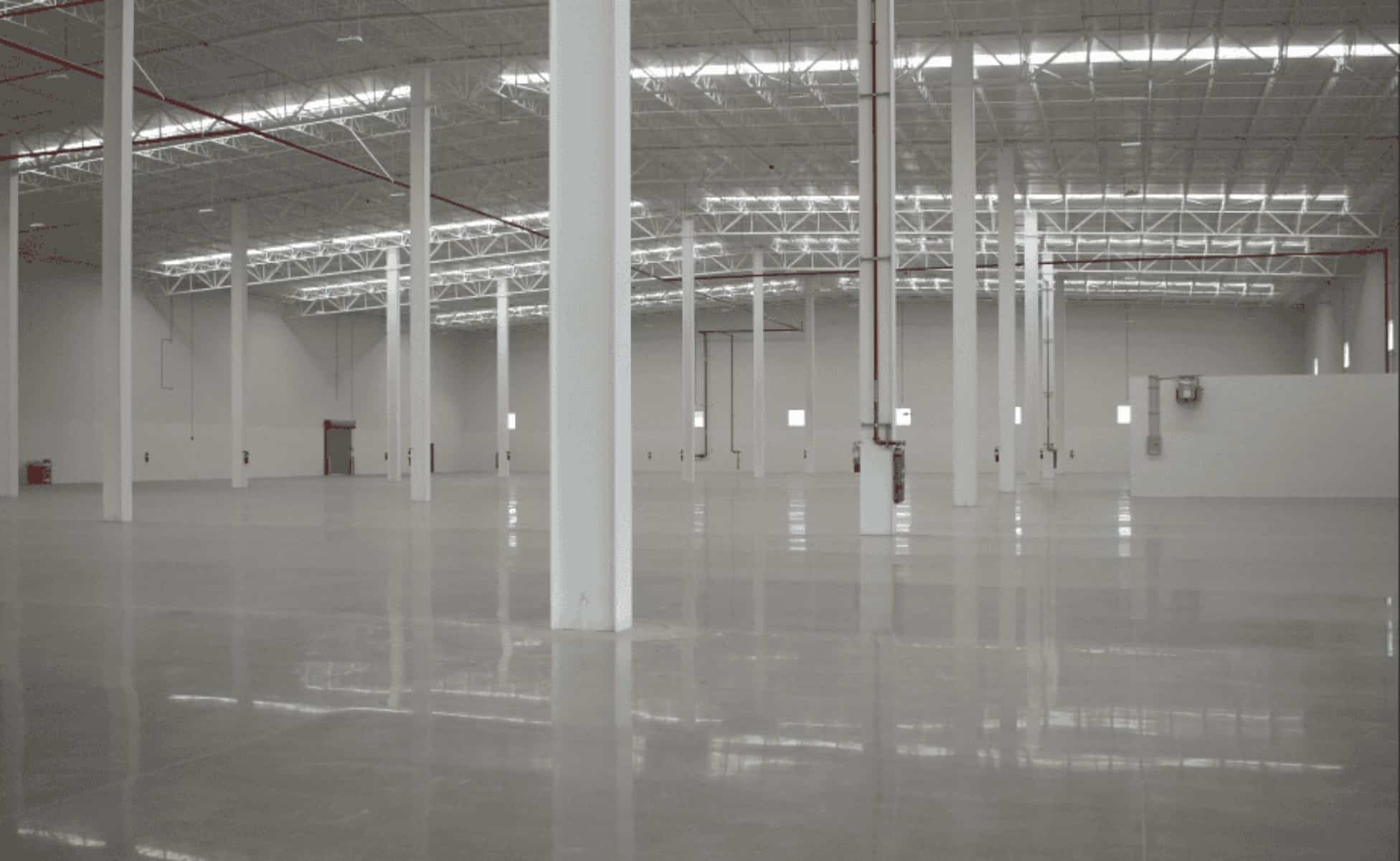 queretaro-industrial-parks-complete-guide-automotive-manufacturing-zones-3_oficial Interior of a large, empty Class A industrial warehouse bay with polished concrete floors and steel roof trusses, representing available industrial space in Mexico.