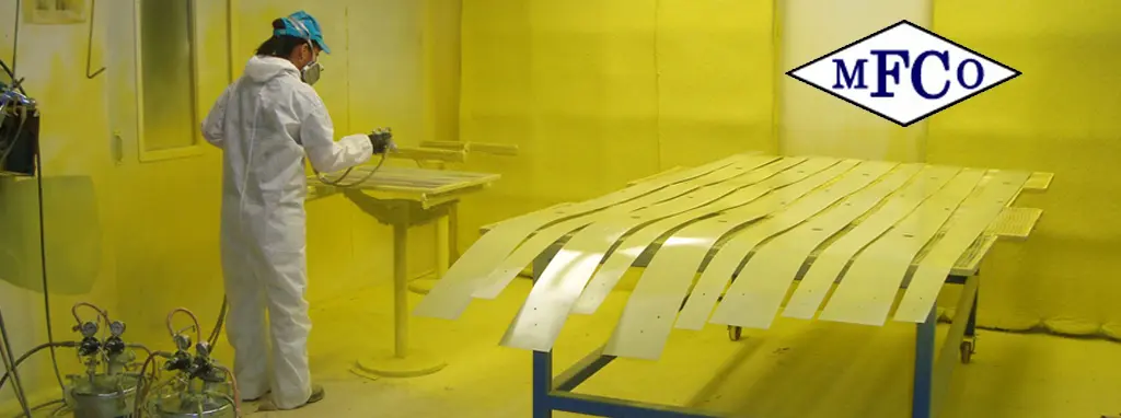 Technician applying coating in a paint booth at Metal Finishing Company